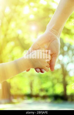 Maman et fille mains sur fond ensoleillé de nature Banque D'Images