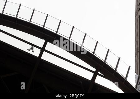 Silhouette d'une personne marchant sur la plateforme transparente au premier étage de la Eiffel, vue du dessous, Paris Banque D'Images