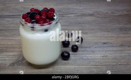 Yaourt grec, lait, smoothie aux bleuets et aux groseilles dans un pot en verre sur une table en bois, un détox, un régime alimentaire Banque D'Images