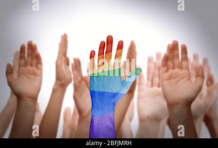 La main de l'homme a peint comme le drapeau arc-en-ciel sur d'autres mains arrière-plan Banque D'Images
