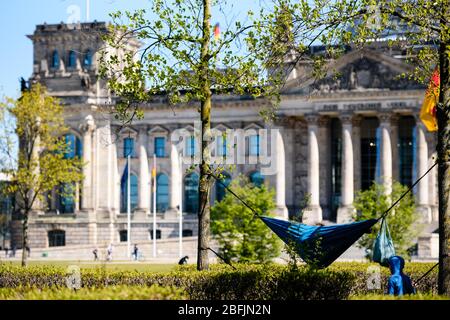 19 avril 2020: Les gens aiment le soleil dans un hamac devant le Reichstag allemand. Les gens aiment le soleil à l'intérieur d'un peuple vivant dans la ville de Berlin doivent rester dans leurs appartements ou l'hébergement habituel pour contenir le coronavirus, les réunions de plus de 2 personnes sont interdites, les restrictions de contact seront maintenues avec une distance minimale de 1,5 mètres. En même temps, le Gouvernement fédéral et les Etats fédéraux ont convenu d'un assouplissement prudent des restrictions à la vie quotidienne, les magasins avec une zone de vente de 800 mètres carrés peuvent rouvrir à Arpil, le 20 sous certaines conditions Banque D'Images