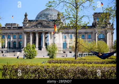 19 avril 2020: Les gens aiment le soleil dans un hamac devant le Reichstag allemand. Les gens aiment le soleil à l'intérieur d'un peuple vivant dans la ville de Berlin doivent rester dans leurs appartements ou l'hébergement habituel pour contenir le coronavirus, les réunions de plus de 2 personnes sont interdites, les restrictions de contact seront maintenues avec une distance minimale de 1,5 mètres. En même temps, le Gouvernement fédéral et les Etats fédéraux ont convenu d'un assouplissement prudent des restrictions à la vie quotidienne, les magasins avec une zone de vente de 800 mètres carrés peuvent rouvrir à Arpil, le 20 sous certaines conditions Banque D'Images