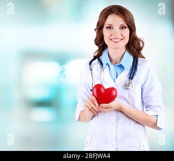 Jeune médecin de belle tenue du coeur sur le fond de l'hôpital Banque D'Images