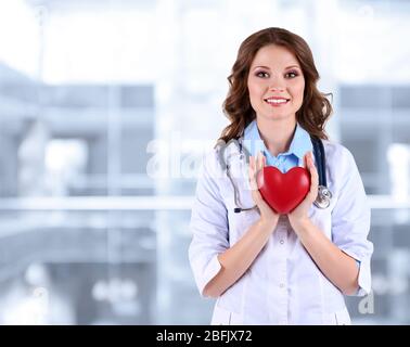 Jeune médecin de belle tenue du coeur sur le fond de l'hôpital Banque D'Images