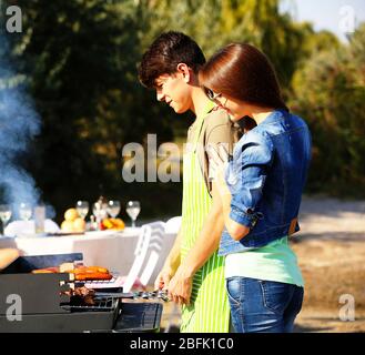 Beau couple avec barbecue, plein air Banque D'Images