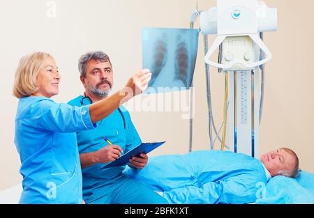 Les médecins discutant du radiogramme de roentgen dans la salle de radiographie avec le patient Banque D'Images