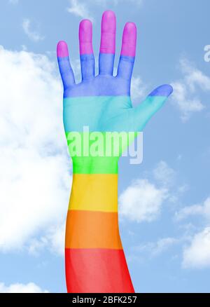La main de l'homme a peint comme le drapeau arc-en-ciel sur fond de ciel Banque D'Images