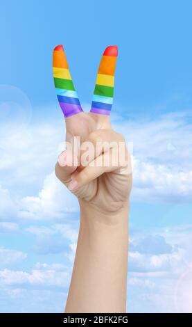 Main de l'homme avec les doigts peints comme le drapeau arc-en-ciel isolé sur blanc Banque D'Images