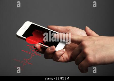 Mains tenant le smartphone mobile avec l'application d'annuaire de santé à l'écran. Banque D'Images