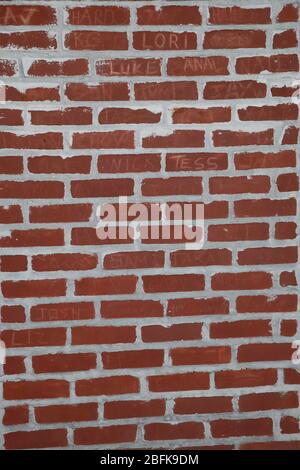 mur de briques rouges avec lignes de ciment blanc et noms gravés dans les briques Banque D'Images