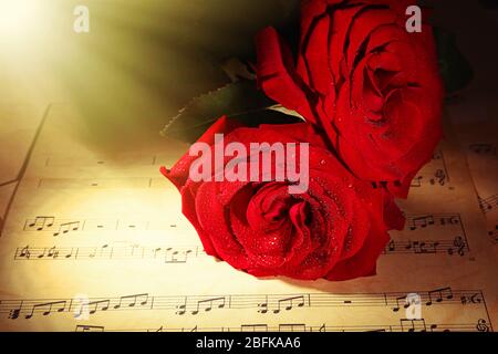 Belles roses rouges sur les feuilles de musique, gros plan Banque D'Images