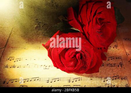 Belles roses rouges sur les feuilles de musique, gros plan Banque D'Images