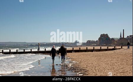 Plage de Portobello, Édimbourg, Écosse. 19 avril 2020. Les gens qui font leurs exercices quotidiens sur la plage par temps ensoleillé, une nageur sauvage féminine bravant le surf fraisky, moins de gens qu'hier, comme le Lockdown de Coronavirus continue, Cependant, la Promenade était animée avec des cyclistes comme toujours, plus que la plage, bien que la plage de sable puisse être plus facile pour les marcheurs à s'isoler. Température de 10 degrés avec un vent ENE de 17 km/h de rafale potentielle de 33 km/h. Crédit: Arch White/Alay Live News. Banque D'Images