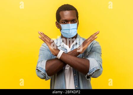 Portrait de l'homme absolument convaincu i avec masque médical chirurgical se tenant à travers les mains, montrant x signe signifiant arrêt, il n'y a aucune façon, finir. indoo Banque D'Images