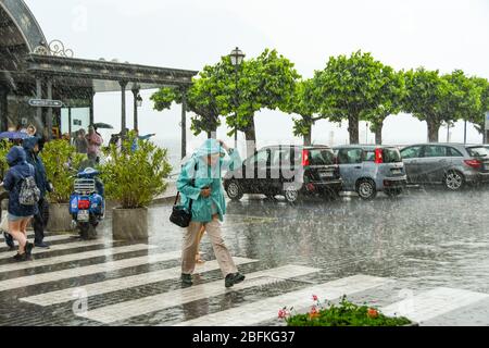 BELLAGIO, LAC DE CÔME, ITALIE - JUIN 2019: Personne marchant à travers un passage piéton pendant une très forte tempête de pluie à Bellagio sur le lac de Côme. Banque D'Images