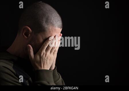 un homme pleure sur son visage avec ses mains Banque D'Images