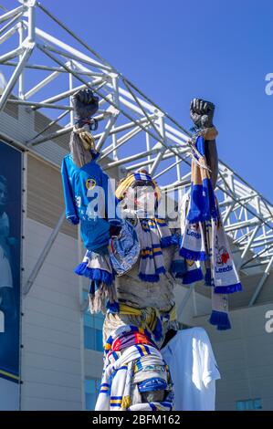 Statue de Billy Bremner avec drapeaux (et masque Covid). Memorial to Leeds United footballer Norman Hunter (29 octobre 1943 – 17 avril 2020). Footballeur anglais qui a joué pour Leeds United, Bristol City, Barnsley et l'Angleterre. Il a fait partie de l'équipe gagnante de la coupe du monde de la FIFA de 1966, qui a reçu la médaille du gagnant en 2007. Hunter, qui a fait 28 apparitions pour l'Angleterre, a été admis à l'hôpital le vendredi 10 avril 2020 avec le coronavirus et est mort à l'âge de 73 ans le vendredi 17 avril suivant. Banque D'Images