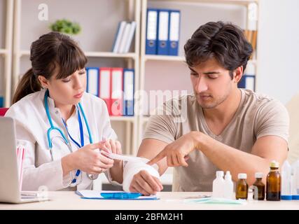 Jeune homme au bras bandé visiter médecin femme traumatologist Banque D'Images