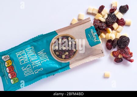 Paquet de chocolat blanc et de fruits à baies de sélection naturelle ouvert avec le contenu renversé sur fond blanc - regardant vers le bas par dessus Banque D'Images