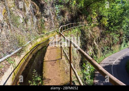 Promenade pavée de levada avec rampe en bois sur le côté et au-dessus d'une route dans les mountines au-dessus du village de Monte sur Madère Portugal. Banque D'Images