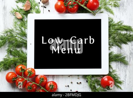 Menu Low-Carb sur l'écran du Tablet pc avec des herbes et légumes frais sur fond de bois Banque D'Images