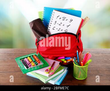 Sac rouge avec équipement scolaire sur table en bois en classe Banque D'Images