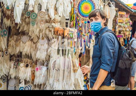 Homme en masque médical sur un marché à Ubud, Bali. Boutique de souvenirs typique vendant des souvenirs et des objets d'artisanat de Bali au célèbre marché d'Ubud, Indonésie Banque D'Images