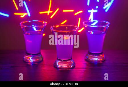 Trois boissons à la fête. Trois prises de vue avec cocktails au bar. Liqueur, vodka, frais. Brillant sur un fond coloré. Nuit club, après la fête. Banque D'Images