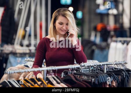 Une magnifique fille reçoit un appel téléphonique dans un magasin. Banque D'Images