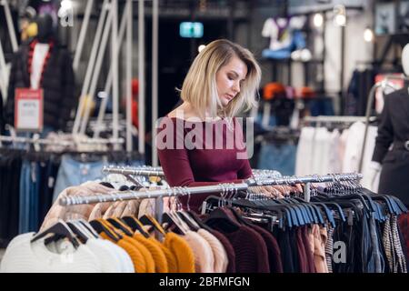 Une jeune femme dans un centre commercial achetant des vêtements. Banque D'Images