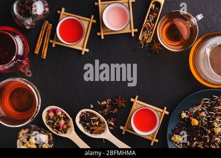 Une table avec divers thés rouges, roses et noirs frais dans des tasses en verre et des théières, une boisson fraîche faite d'un mélange de feuilles de thé sèches et d'épices sur un bac à blé Banque D'Images