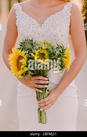 femme tenant bouquet de tournesol au coucher du soleil. photo de mariage de beaux-arts. Bouquet de fleurs de soleil pour mariage. Banque D'Images