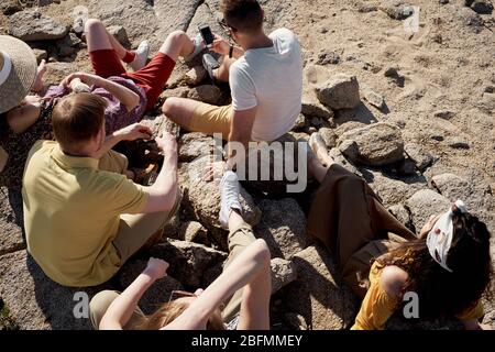 Vue panoramique sur les jeunes assis sur les rochers de la plage, se détendre et bronzer tout en passant un week-end d'été ensemble Banque D'Images