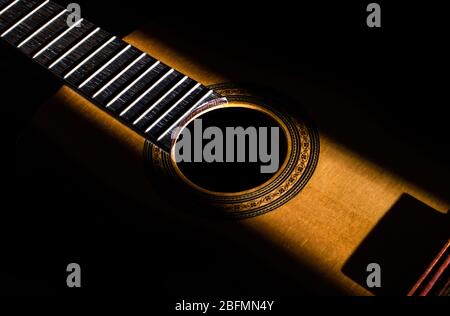 Fond abstrait d'une guitare dans l'obscurité. Partie centrale d'une guitare éclairée par une radiographie de la lumière du soleil. Banque D'Images