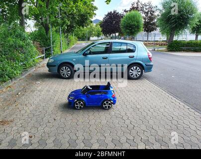 Deux voitures restent près du parking en été et des arbres autour. Voiture bleue pour enfant et voiture verte pour adulte debout côte à côte. Banque D'Images