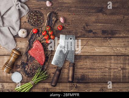 Tranche de boeuf cru sirlion steak sur planche en bois avec des tomates, l'ail et les asperges et la viande hache sur la table de cuisine et arrière-plan. Banque D'Images