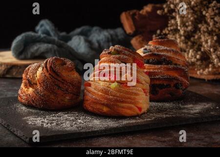 Kraffins aux raisins secs, fruits confits et graines de pavot, arrosés de sucre en poudre. Banque D'Images