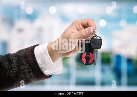 Homme d'affaires tenant la clé de voiture sur fond lumineux Banque D'Images
