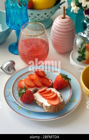 Toasts au fromage frais accompagnés de fraises accompagnés d'une boisson rouge. Banque D'Images