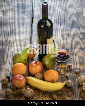 Les fruits alignés sur la table sont à côté d'un verre de vin et d'une bouteille Banque D'Images