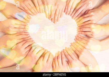 Beaucoup de doigts de faire la forme de coeur sur fond en bois avec la lumière Banque D'Images