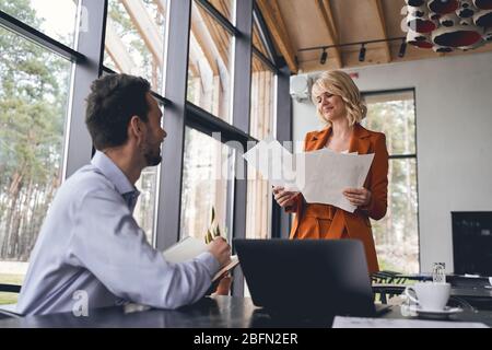 Homme avec un journal regardant une femme designer Banque D'Images