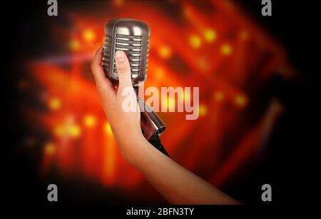 Microphone rétro dans la main féminine sur fond de rayons laser Banque D'Images