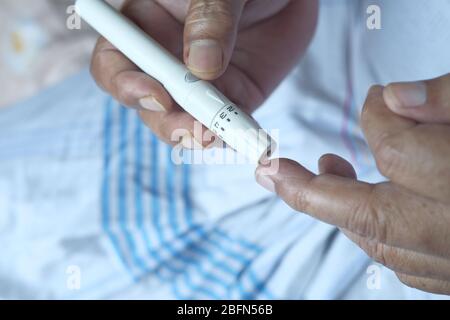 homme senior avec glucometer vérifiant le taux de sucre dans le sang à la maison. Banque D'Images