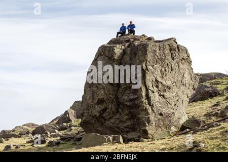 Grimpeurs assis sur le dessus de la pierre de Pudding, un grand bloc dans la vallée de Boulder, Coniston, Cumbria Banque D'Images