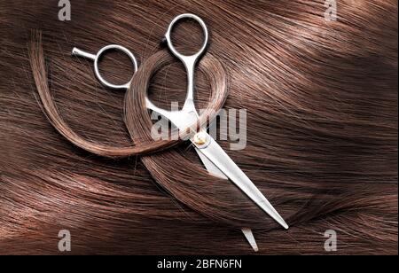 Ciseaux de coiffure avec des cheveux bruns foncés, Close up Banque D'Images