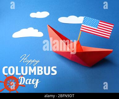 Texte HAPPY COLUMBUS JOUR avec bateau en papier et drapeau des États-Unis sur fond bleu. Concept national de vacances. Banque D'Images