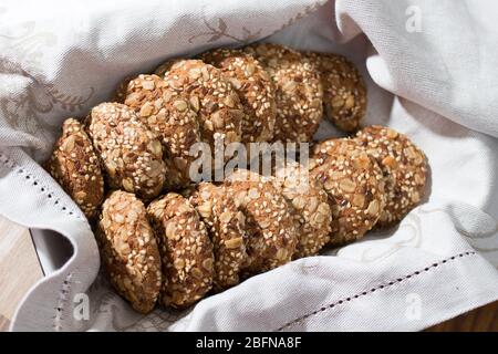 Les biscuits au gruau, saupoudrés de graines de sésame et d'amandes, sont dans une serviette beige dans un plat de cuisson après la cuisson. Cuisson Banque D'Images