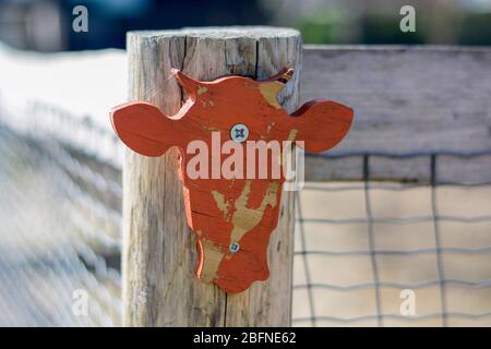 Tête de vache en bois à l'eau orange fixée à une clôture à l'entrée d'un zoo pour enfants Banque D'Images