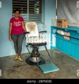 Coiffeur cubain debout à côté d'une chaise de salon de coiffure à l'extérieur, Viñales, Cuba Banque D'Images